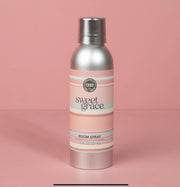 A bottle of Sweet Grace room spray with a pink label on a pink background.