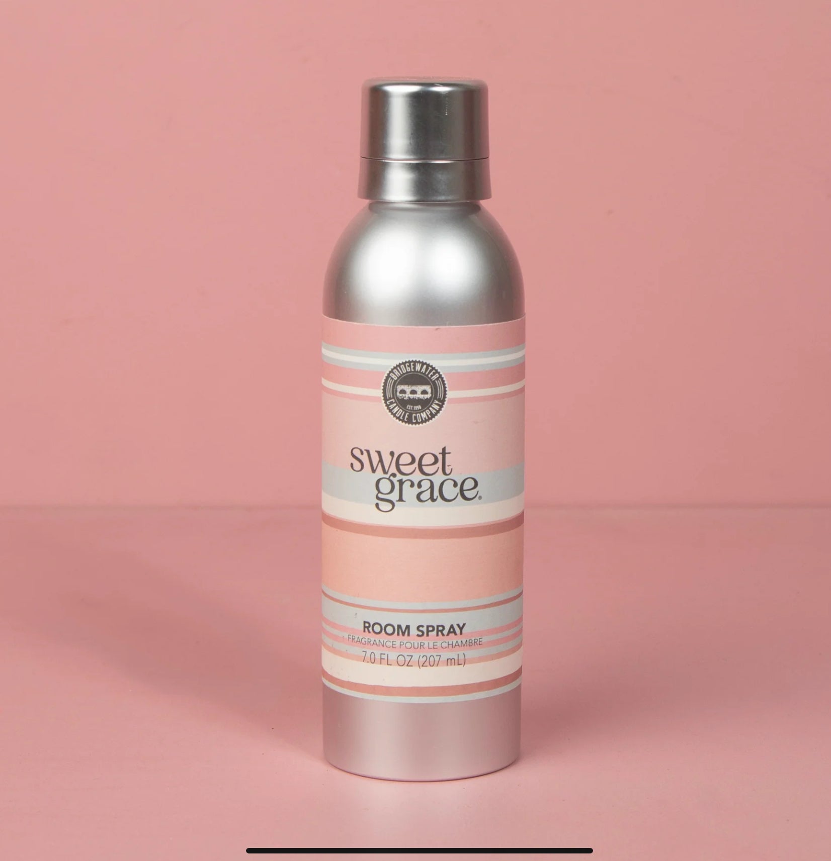 A bottle of Sweet Grace room spray with a pink label on a pink background.