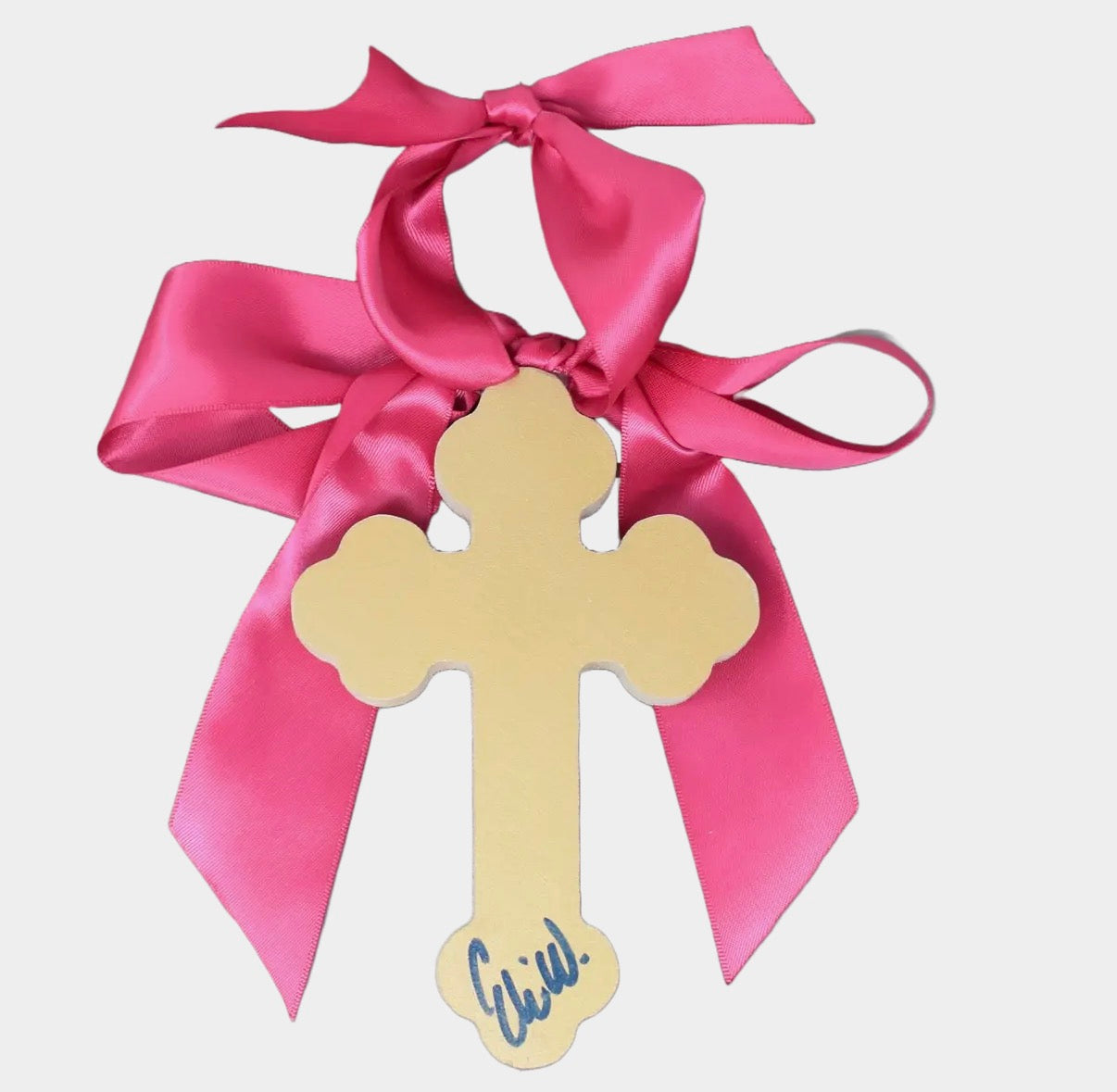 Decorative cross with pink ribbon and 'Cristina' written on it against a light gray background