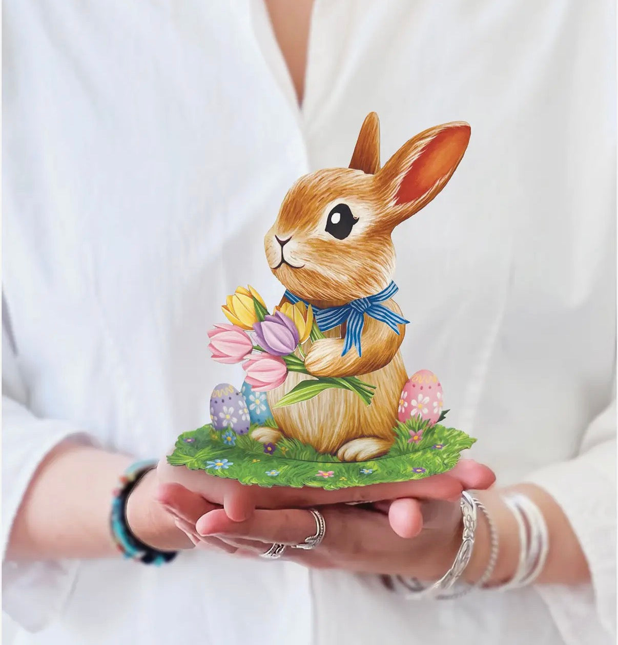 Person holding a card with a rabbit illustration and Easter elements.