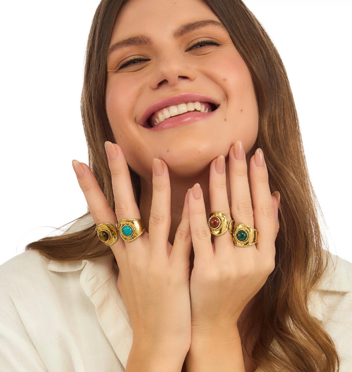 Woman wearing gold rings with gemstones on a white background