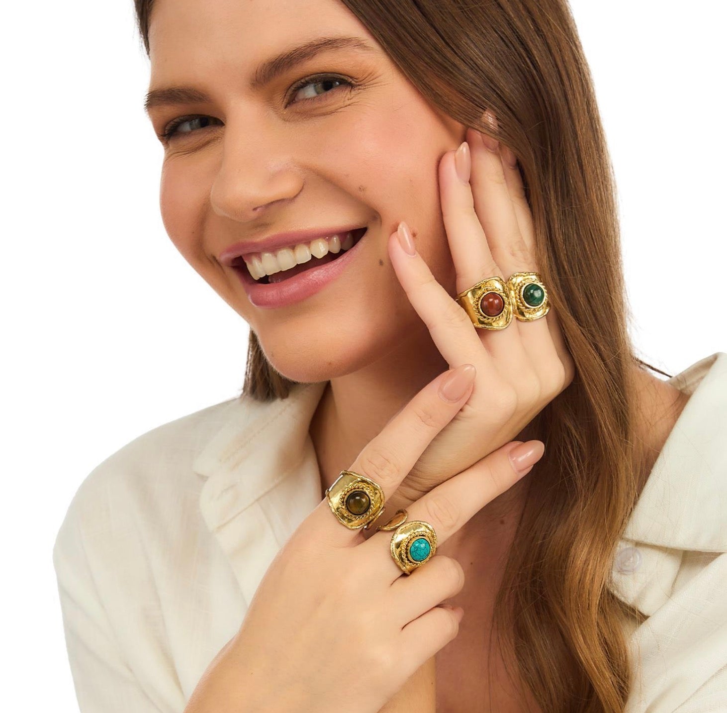 Woman wearing gold rings with gemstones on a white background