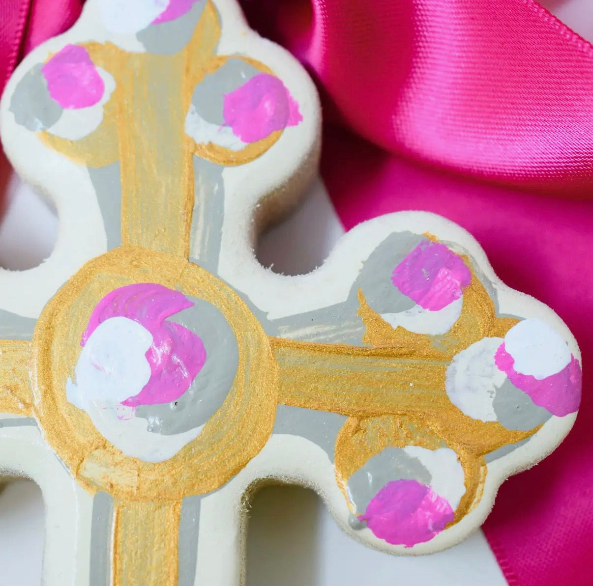 Decorative cookies shaped like keys with gold, pink, and gray icing on a pink background