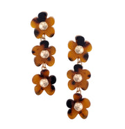 Pair of floral earrings with tortoiseshell and gold accents on a white background