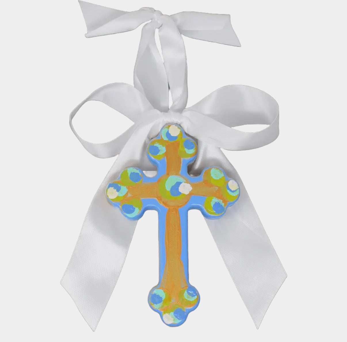 Decorative cross ornament with colorful patterns and a white ribbon on a white background