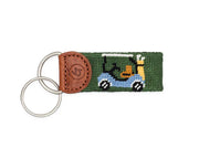 Keychain with green fabric strap featuring a cartoon character and brown leather accent on a white background