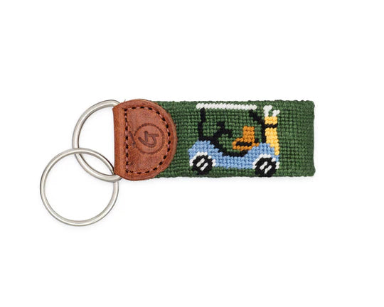 Keychain with green fabric strap featuring a cartoon character and brown leather accent on a white background