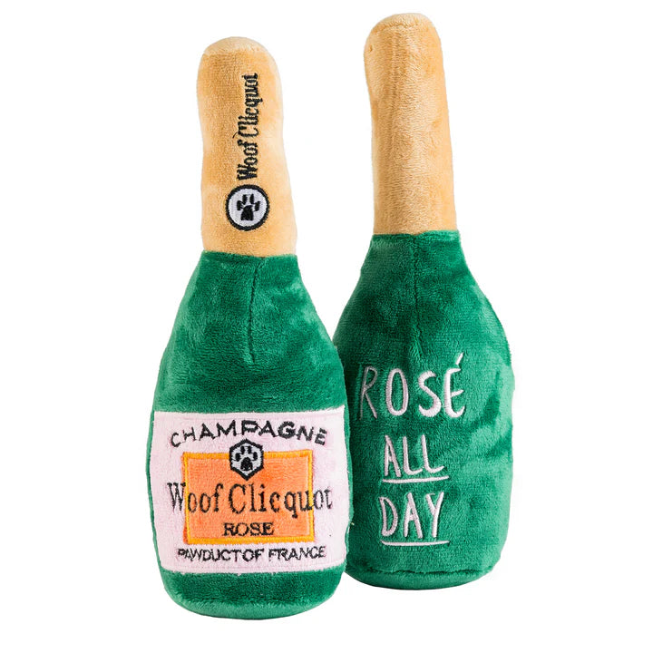 Two plush champagne bottle toys with 'Woof Clicquot' branding on a white background