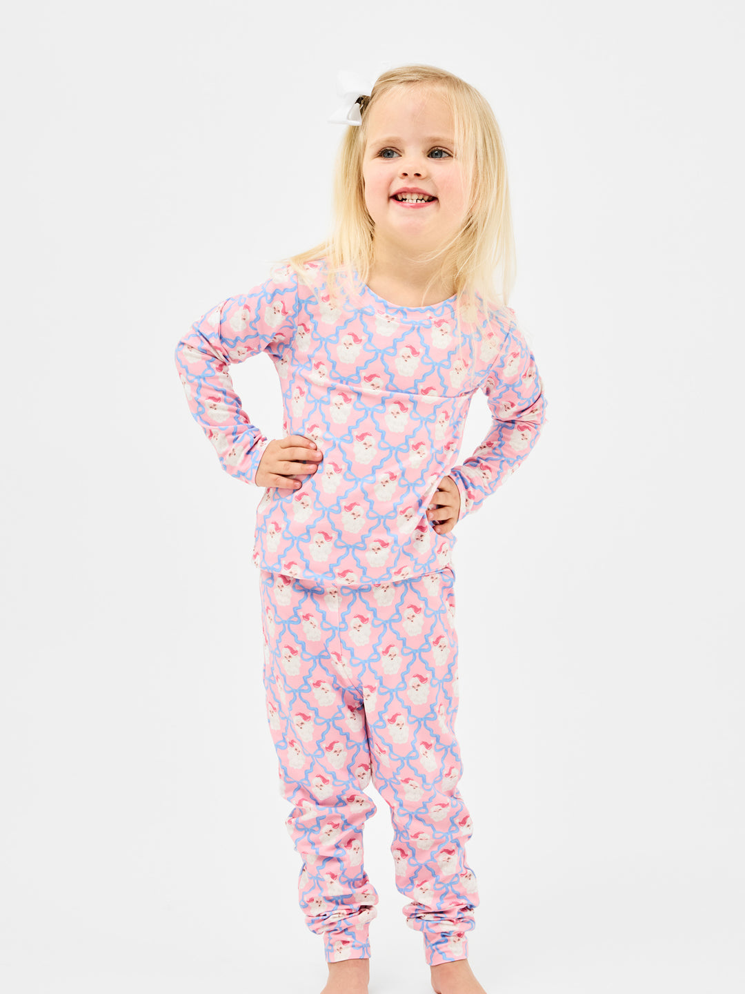 Young girl wearing a pink and blue patterned onesie on a white background