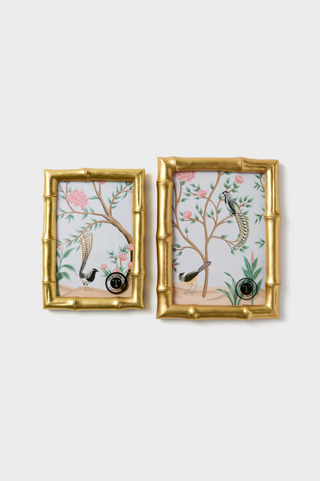 Two gold-framed wall art pieces with floral and bird designs on a white background