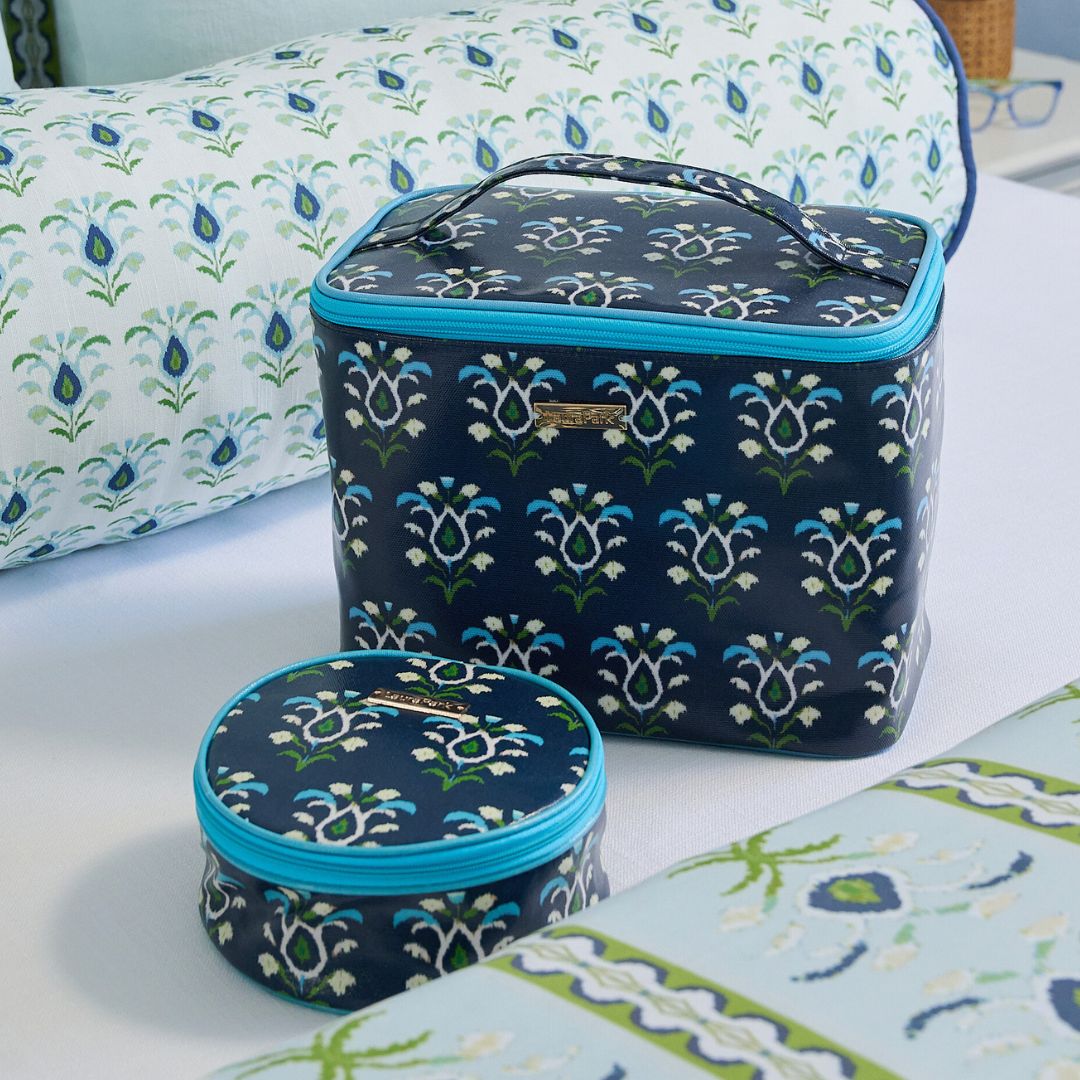 Set of two floral-patterned containers with blue zippers on a floral-patterned surface.