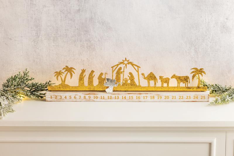Gold nativity scene Advent calendar on a white surface with decorative elements.