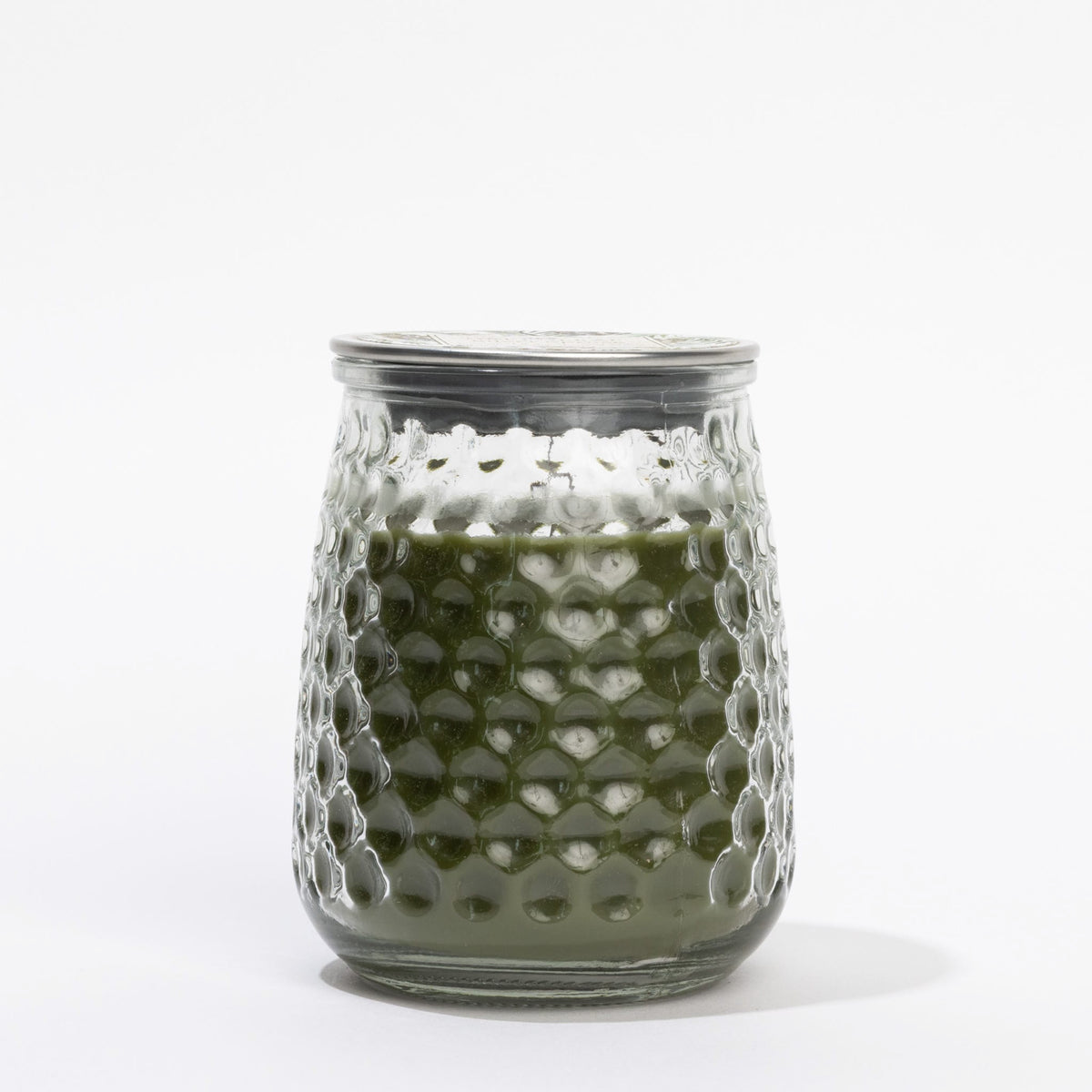 Clear textured glass tumbler with green liquid on a white background