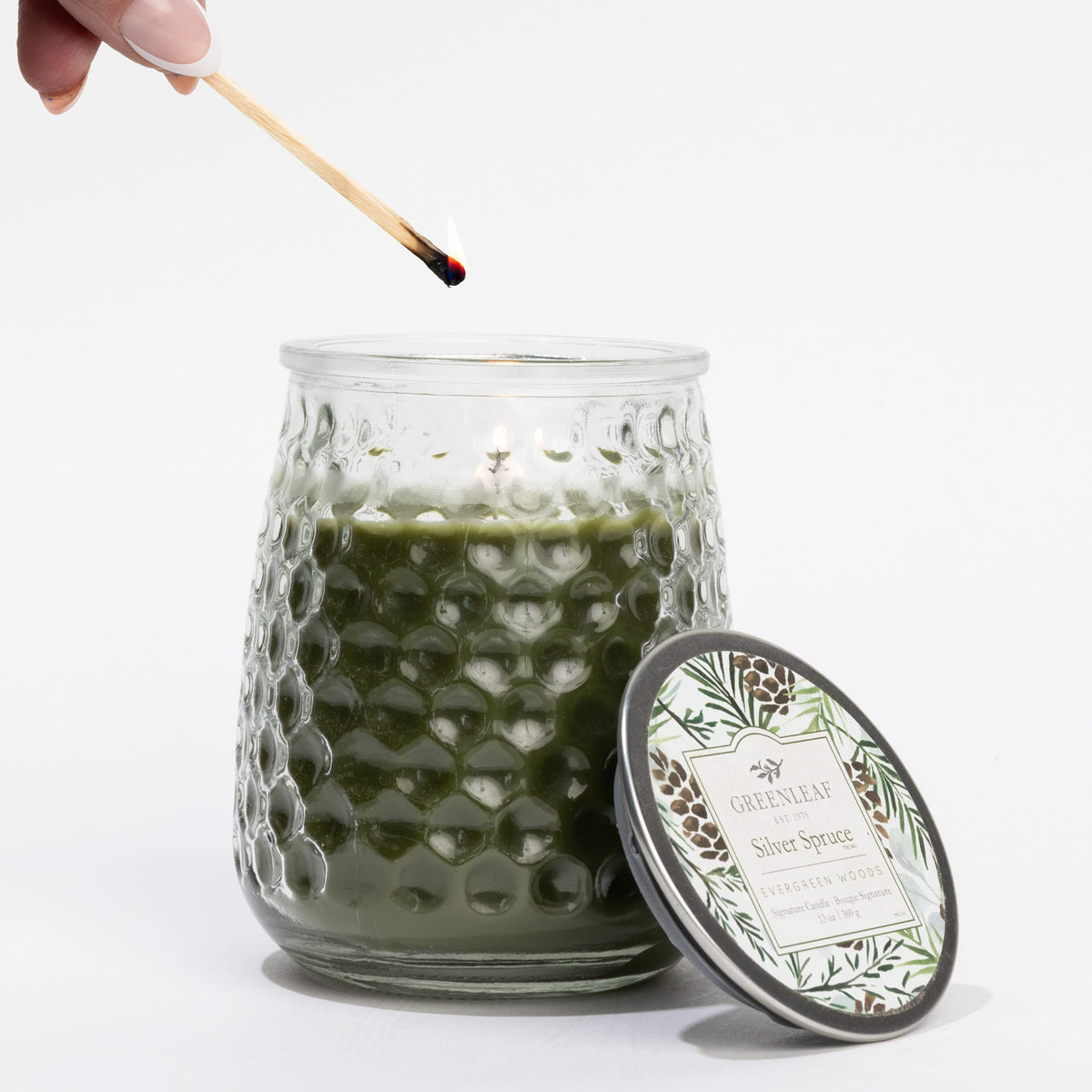Green candle being lit with a match on a white background