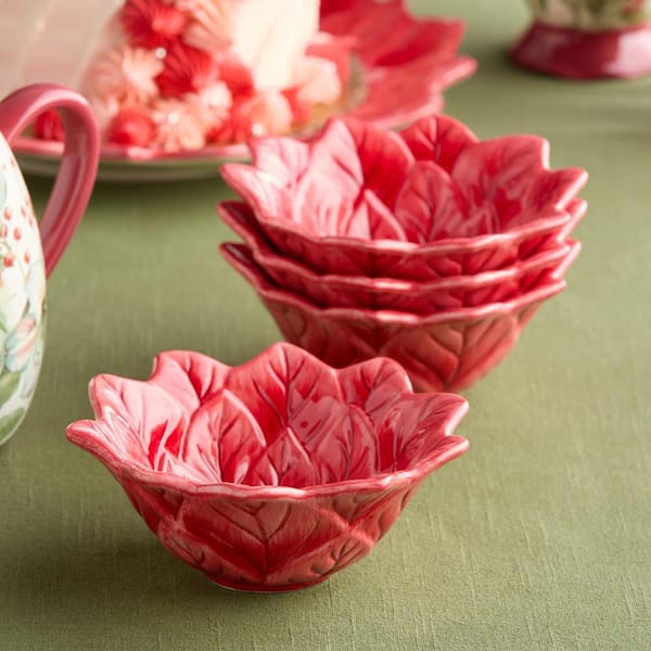 Set of red ceramic leaf-shaped bowls on a green surface