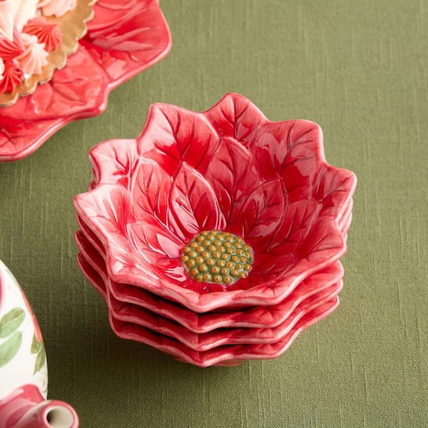 Stack of red ceramic flower-shaped dishes on a green background