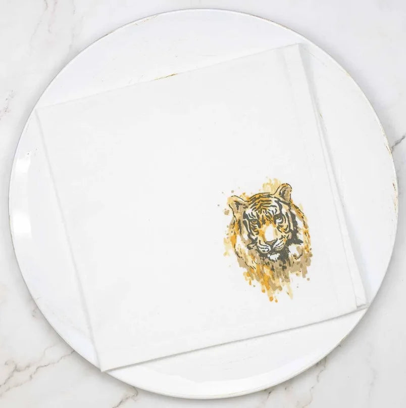 Round white plate with a gold tiger design napkins by Royal Standard on a marble surface