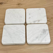 Four square marble coasters with a tiger face design by The Royal Standard on a wooden surface