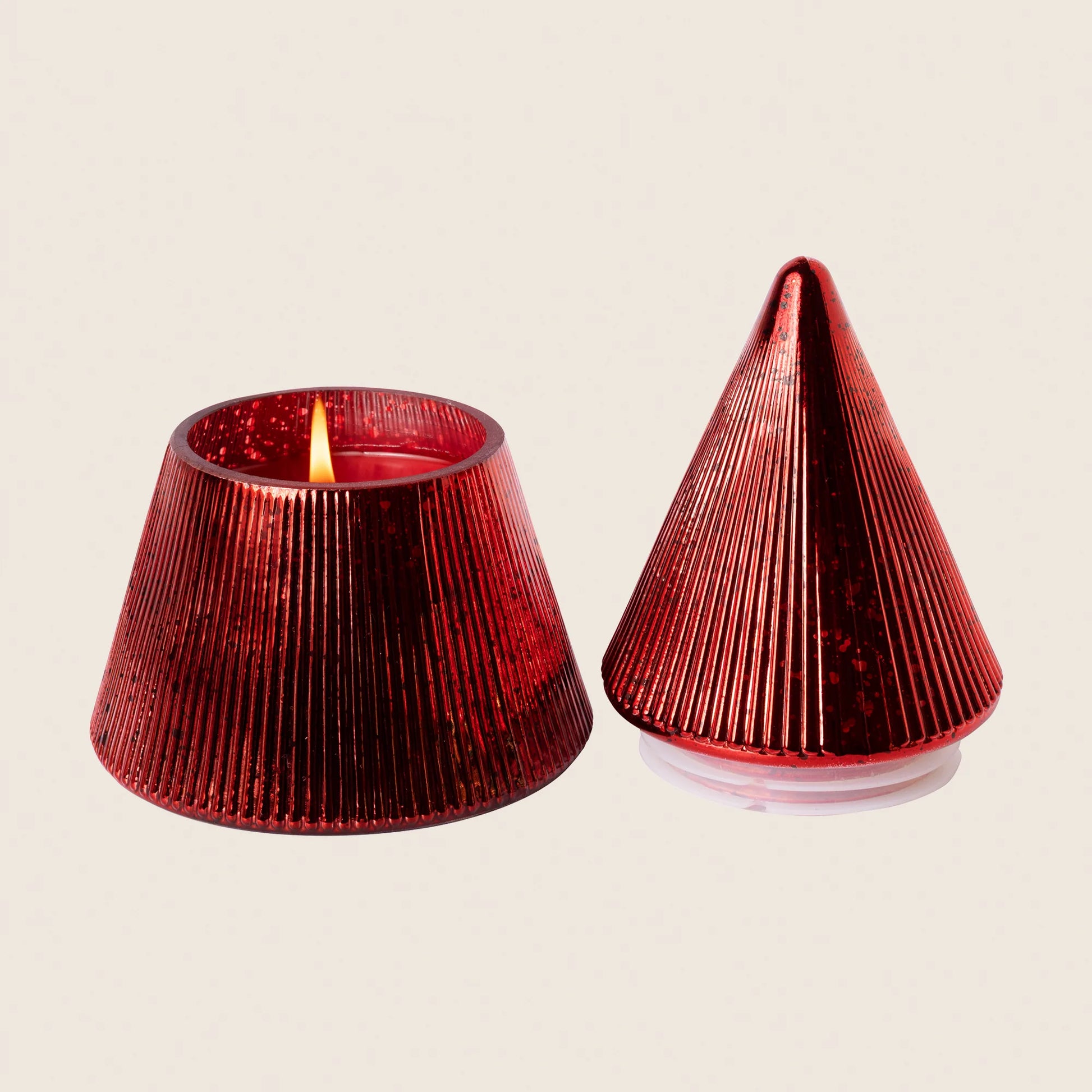 Red tree shaped jar candle - beige background - candle is lit