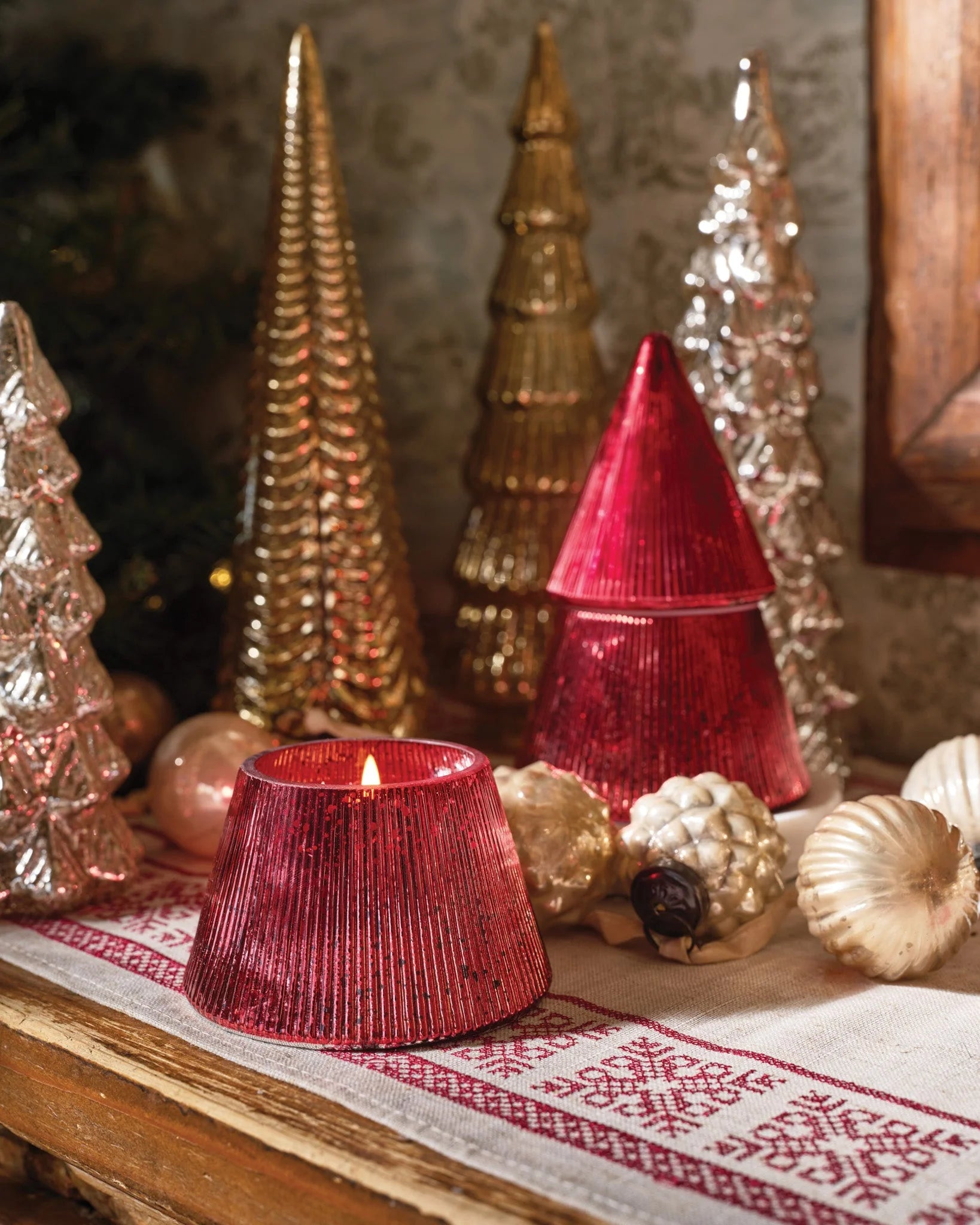 Red tree shaped jar candle on a seasonal table.  