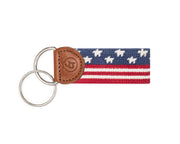Keychain with a needpoint American flag pattern and leather accent on a white background