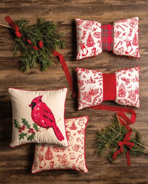 Set of Christmas-themed decorative pillows with red and white patterns on a wooden surface.