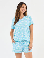 Woman wearing a light blue pajama set with white floral pattern on a white background