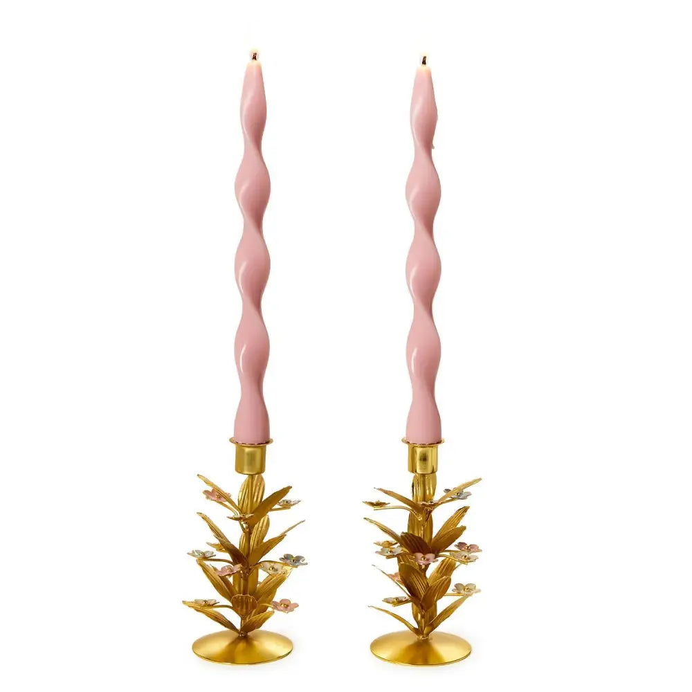 Pair of pink twisted candles on gold candle holders against a white background