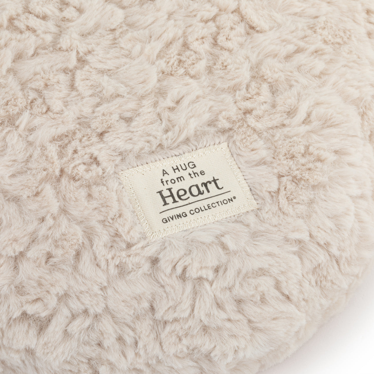 Close-up of a textured beige blanket with a 'Hug from the Heart' label.