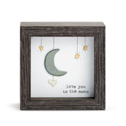 Decorative wall art with a moon and stars design in a wooden frame on a white background.