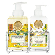 Two bottles of Michel Design Works Lemon Basil hand soap and lotion in a metal caddy on a white background.