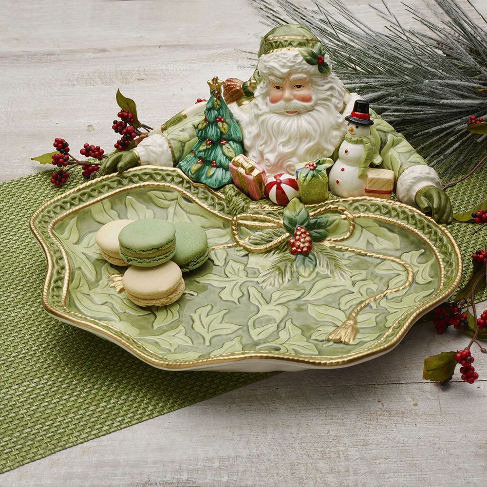 Decorative plate with a Santa Claus figure and Christmas-themed cookies on a wooden surface.