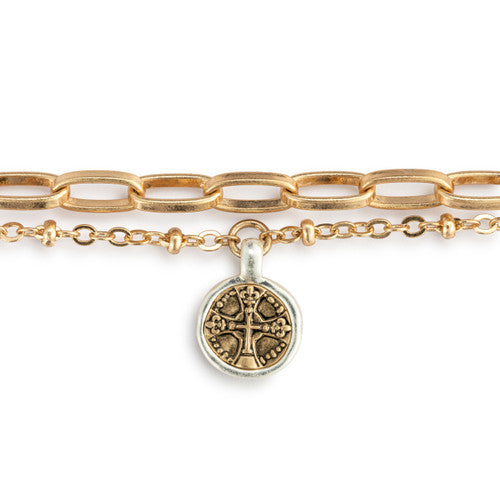 Gold chain bracelet with a silver charm featuring a Celtic cross design on a white background.