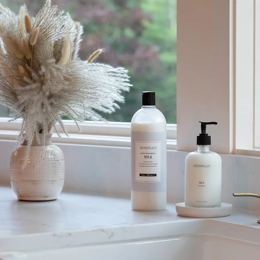 Archipelago Milk Hand Soap in a glass pump bottle on a white background On a sink 