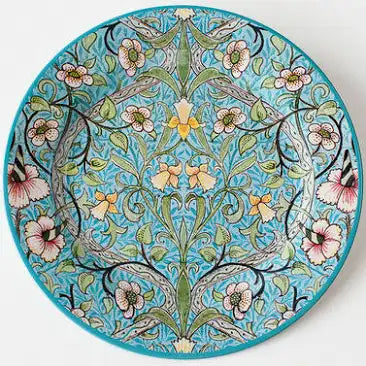 A decorative tin plate with a floral Art Deco design featuring a turquoise background and multicolored flowers and patterns.