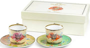 Two floral teacups with saucers in front of a decorative box.