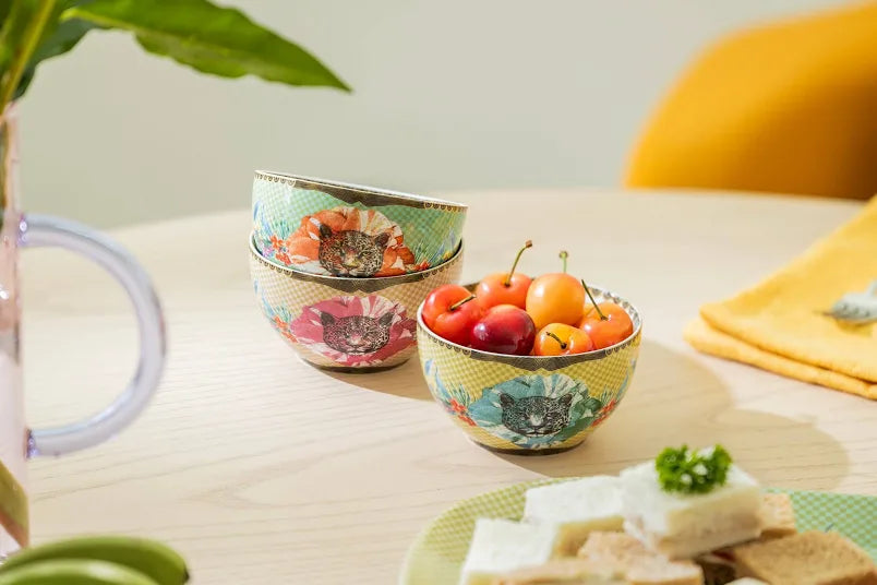 Decorative bowls with floral patterns on a table with fruits and snacks.