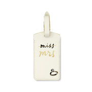 Cream-colored luggage tag with 'Miss Mrs.' text and ring design on a white background