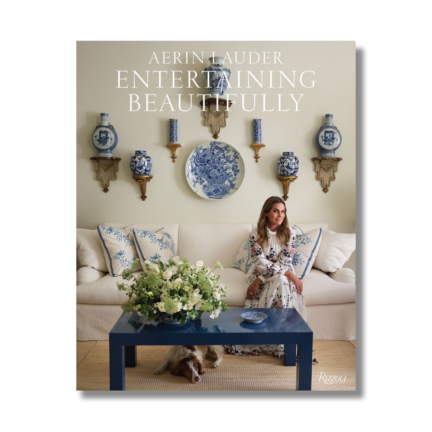 Book cover of 'Aerin Lauder Entertaining Beautifully' with a woman in a living room setting.