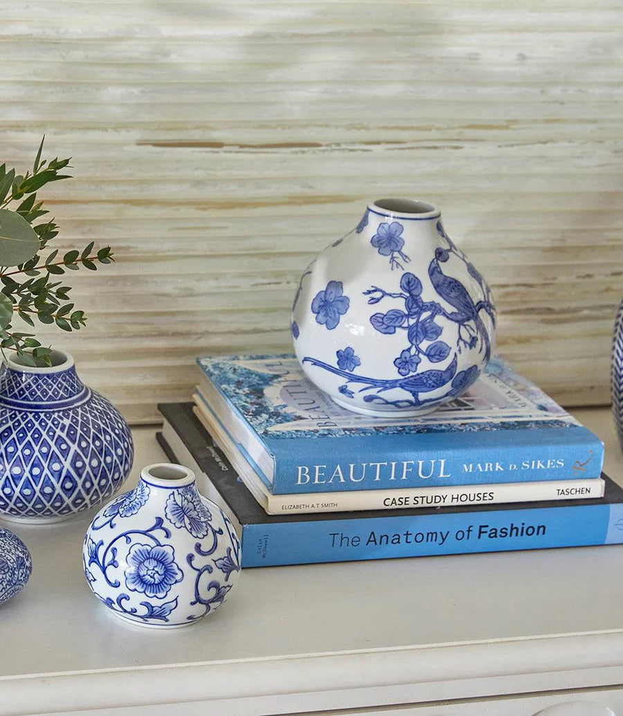 Blue and white ceramic vases on top of books with a plant in the background