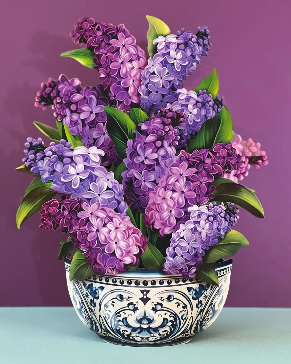 Bouquet of purple and pink flowers in a decorative pot on a light blue surface with a purple background