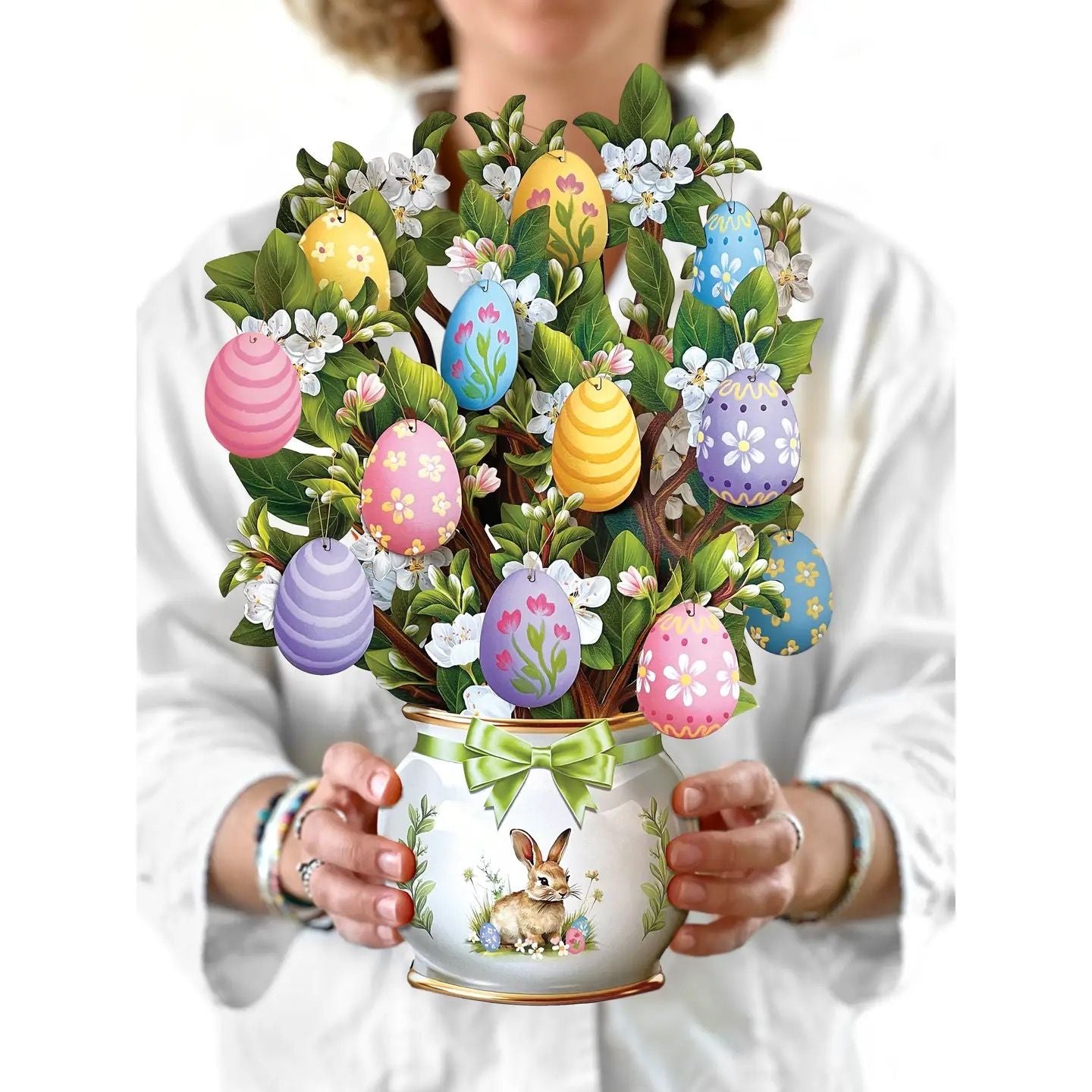 Person holding a decorative Easter-themed mug with colorful eggs and flowers.