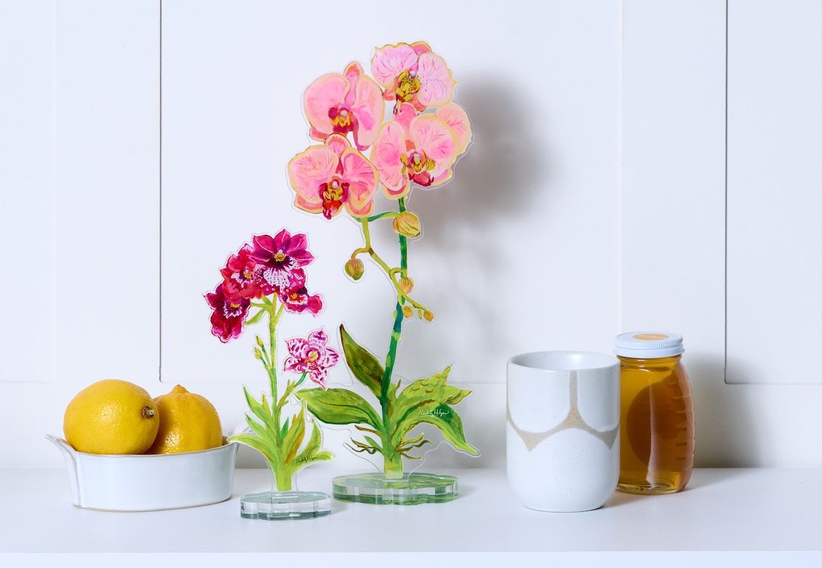 Decorative flowers in a glass vase on a white surface with lemons and a jar of honey.