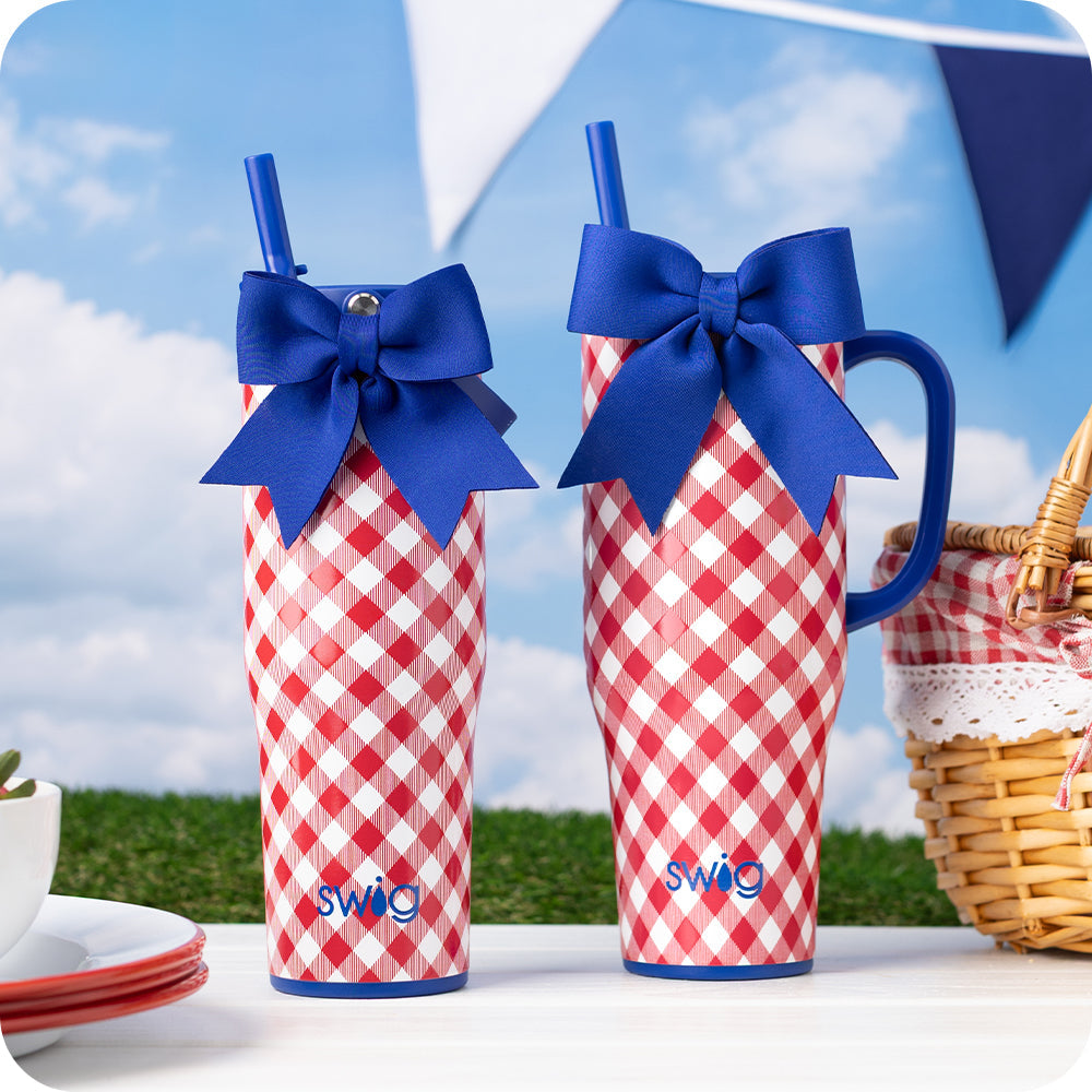 Two red and white check drink tumblers in a picnic setting 