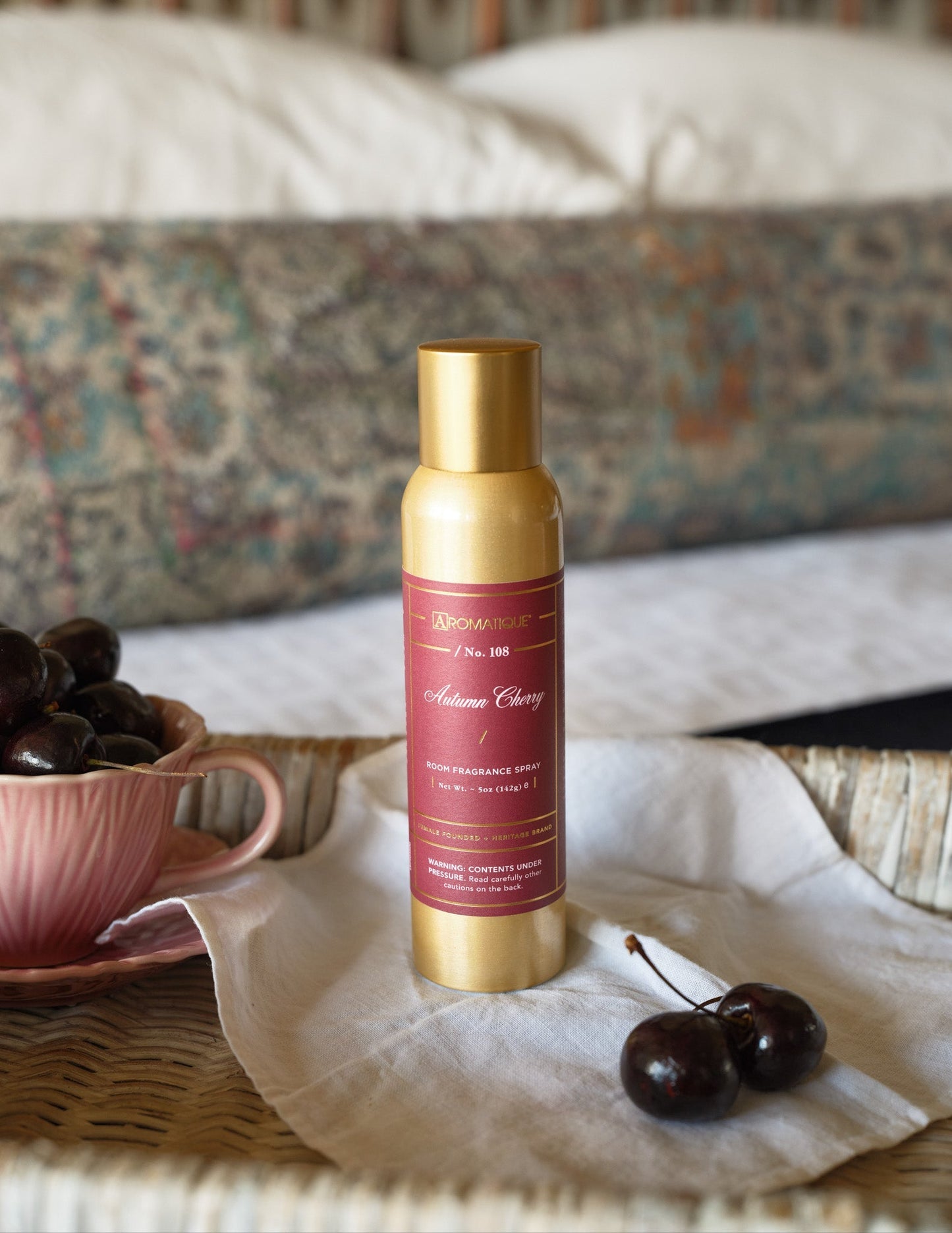 Seasonal - Room Spray - Autumn Cherry - 5 oz. - gold spray can with red label.  Product is sitting on a table with a white table cloth. 