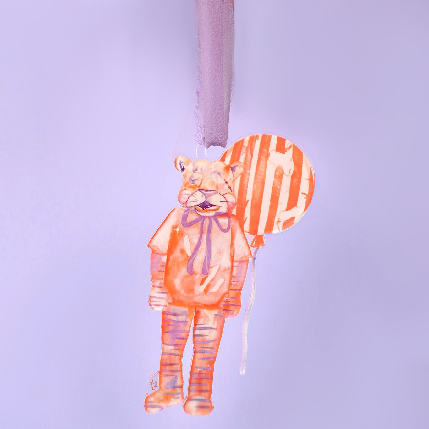 handpainted orange acrylic tiger ornament on ribbon with a striped balloon on a light purple background