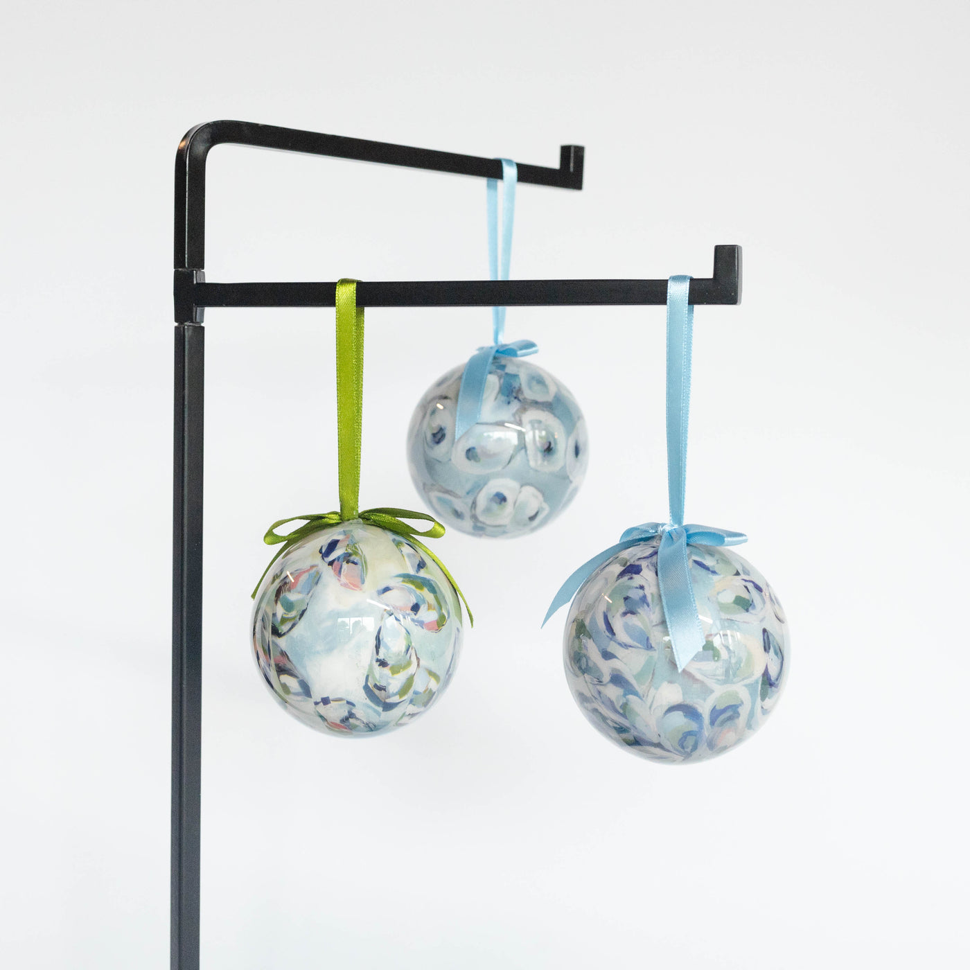 Three shell-patterned ornaments hanging from a stand on a white background