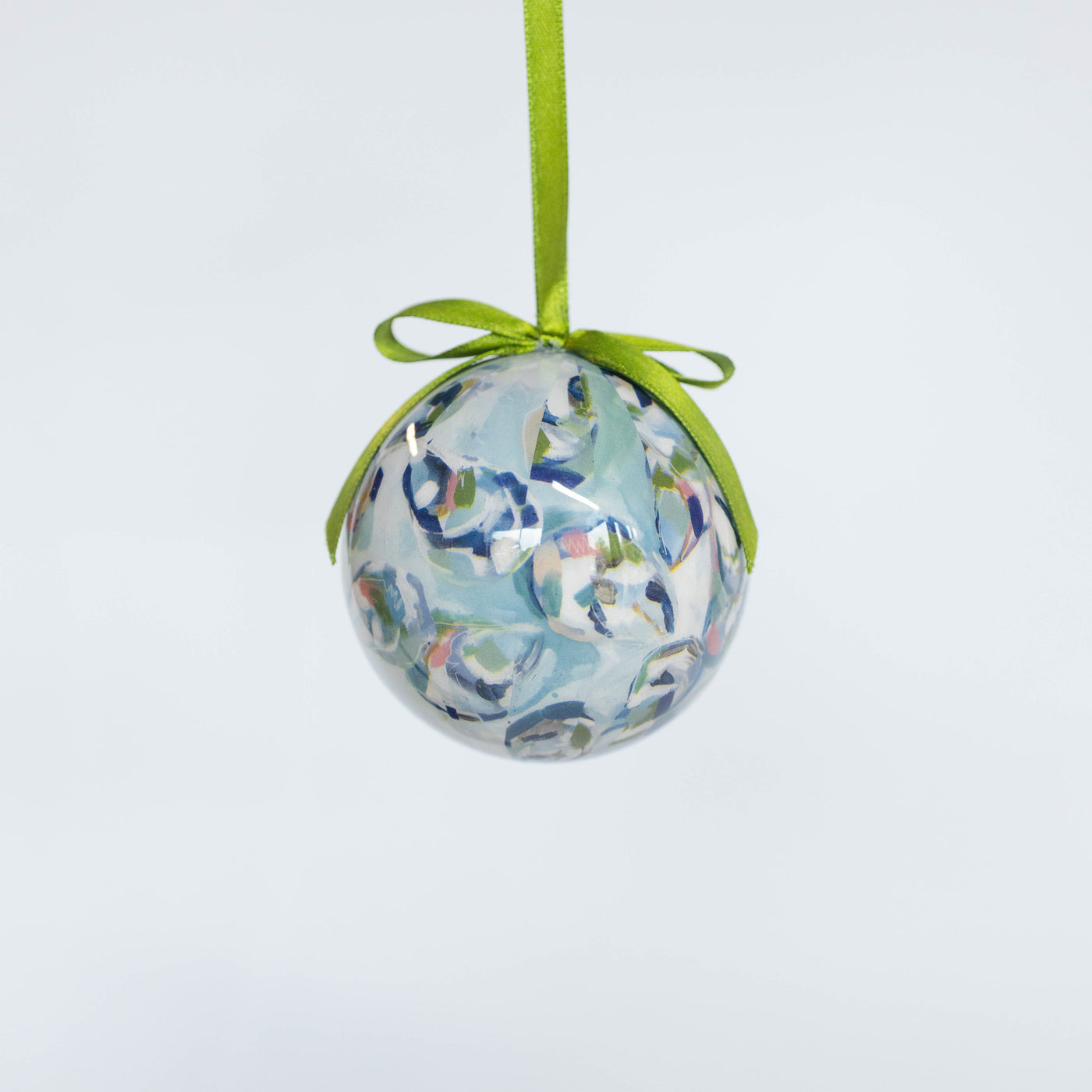 Decorative ball ornament with oyster pattern and green ribbon on a light gray background