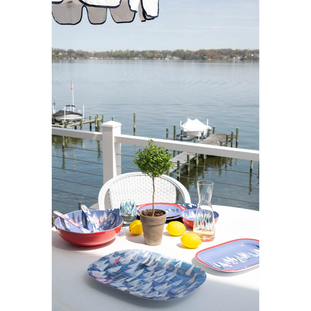 Outdoor table setting with plates, bowls, and lemons by a waterfront.