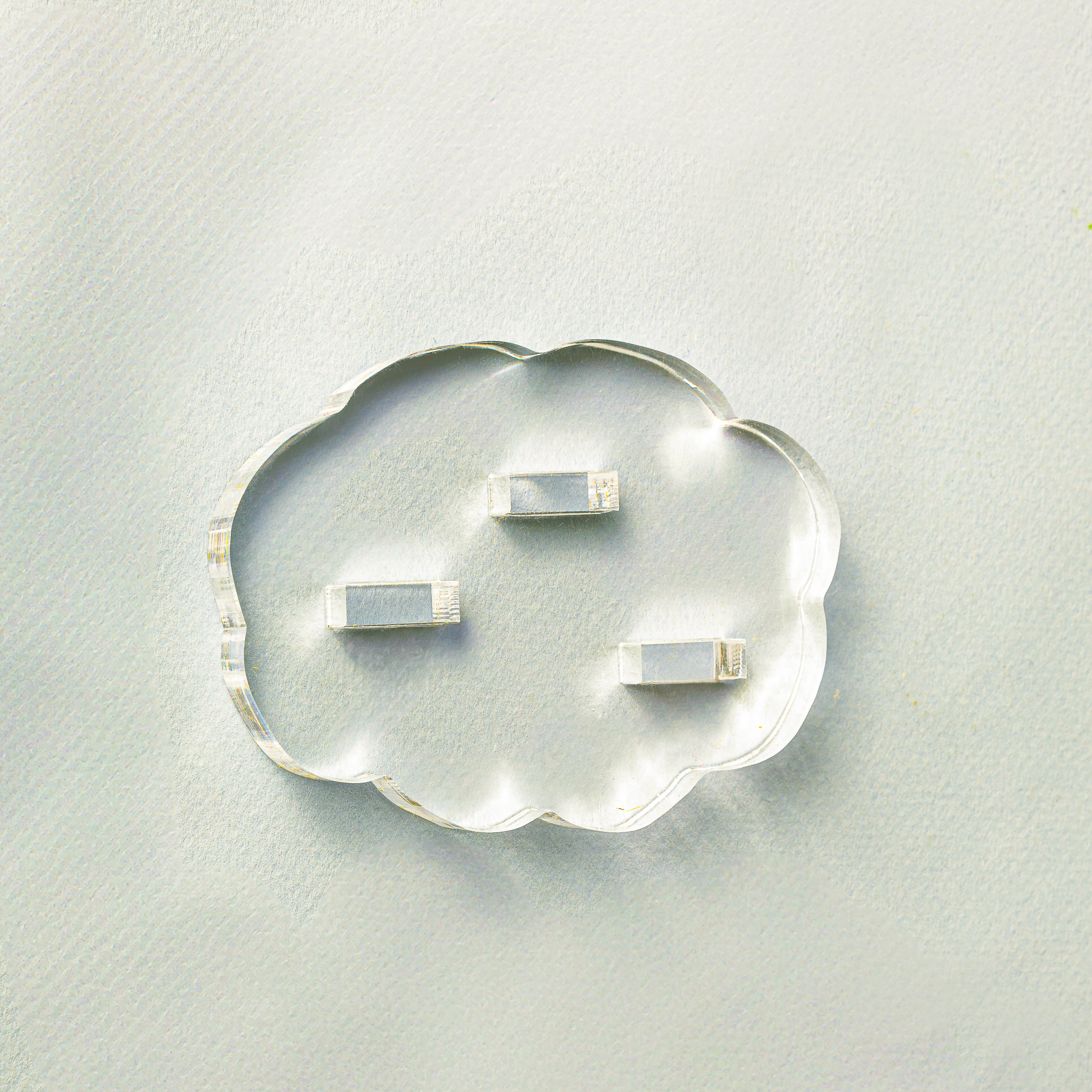 Clear cloud-shaped object with embedded smaller rectangular objects on a light gray background
